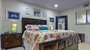 Un dormitorio con una cama grande, una mesita de noche, una lámpara y cuadros en la pared.