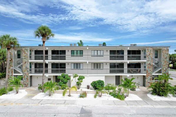A multi-story hotel with balconies, palm trees, and a clear sky. - Inviting condo near beach with enclosed balcony WD and AC snowbirds OK (Clearwater)