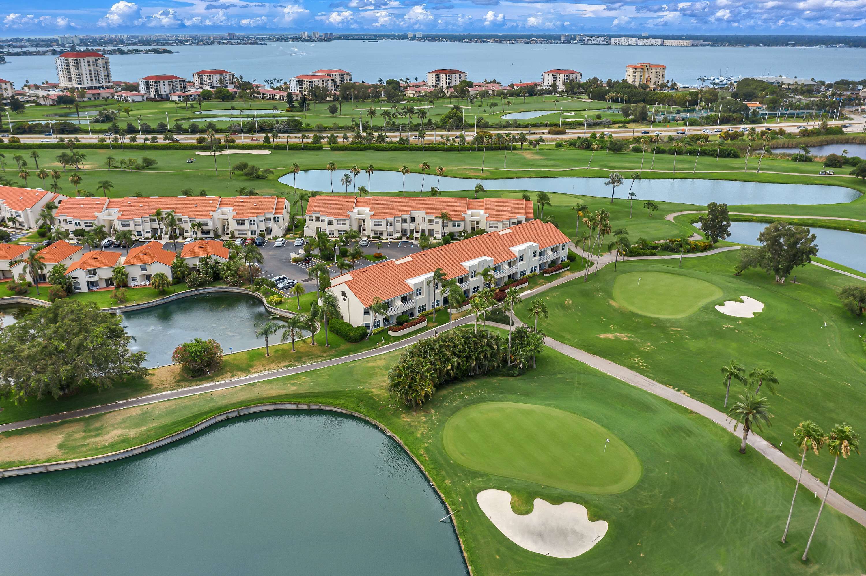 A golf course with bunkers, water hazards, and a clubhouse with red roofs.