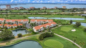 A golf course with bunkers, water hazards, and a clubhouse with red roofs. - Beautiful condo near beaches and activities with pool access and golf course view (St. Petersburg)