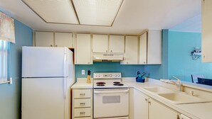 A compact kitchen with white cabinets, a white refrigerator, a stove, and a sink. - Family-Friendly, Canal Front Condo Near Beach | Close to Island Events (Treasure Island)