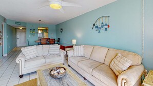 A living room with two sofas, a coffee table, and a ceiling fan. - Family-Friendly, Canal Front Condo Near Beach | Close to Island Events (Treasure Island)
