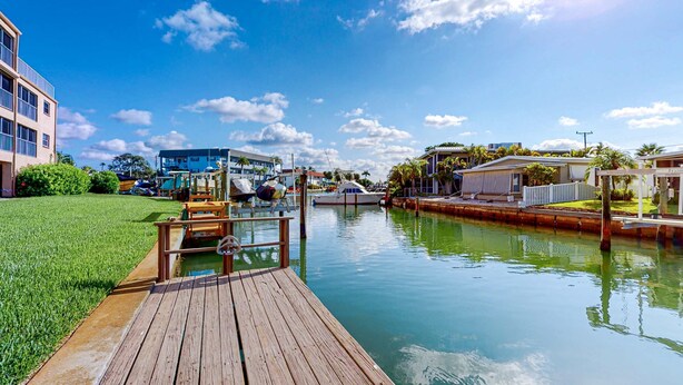 A wooden dock leading to a calm waterway with buildings in the background. - Family-Friendly, Canal Front Condo Near Beach | Close to Island Events (Treasure Island)