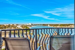A balcony with two chairs, overlooking a body of water and a distant cityscape. - Top floor condo near the beach with pool hot tub washer dryer (Treasure Island)