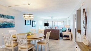 A modern dining area with a round table, white chairs, and a chandelier. - Renovated beachfront condo with heated pool amazing Gulf views and washer dryer (Madeira Beach)