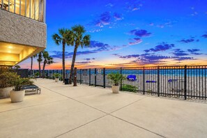 A coastal walkway with a railing, palm trees, and a view of the beach. - Renovated beachfront condo with heated pool amazing Gulf views and washer dryer (Madeira Beach)