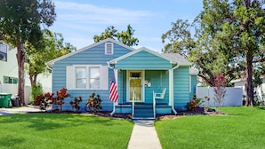 A single-story house with a front porch, a mailbox, and an American flag. - Dog friendly bungalow with a fenced yard deck washer dryer and AC (Tampa)