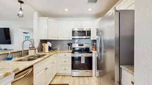 A modern kitchen with white cabinets, stainless steel appliances, and a marble countertop. - Dog friendly bungalow with a fenced yard deck washer dryer and AC (Tampa)