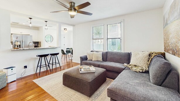 A modern living room with a grey sofa, ottoman, and a ceiling fan. - Dog friendly bungalow with a fenced yard deck washer dryer and AC (Tampa)