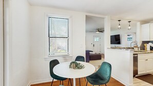 A modern kitchen with white cabinets, a central island, and a dining area with a round table and teal chairs. - Dog friendly bungalow with a fenced yard deck washer dryer and AC (Tampa)
