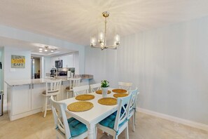A dining area with a white table, blue chairs, and a chandelier.