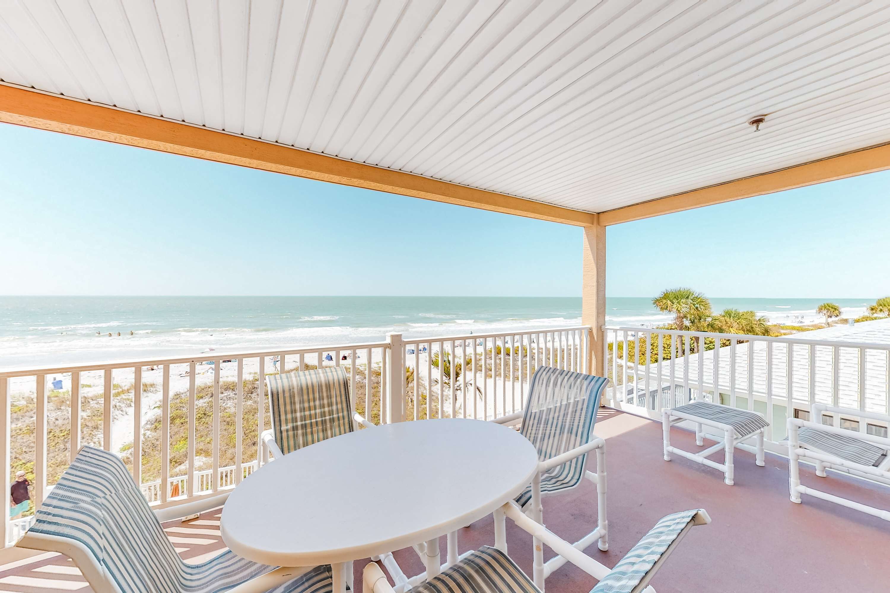 A covered outdoor seating area with a view of the beach and ocean.