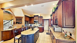 A spacious kitchen with dark wood cabinets, a large island, and a built-in microwave.