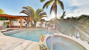 A swimming pool with a pergola and palm trees.