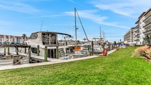 Een jachthaven met aangemeerde boten, een gazon en een gebouw met balkons.