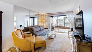 Un salon moderne avec un canapé, un pouf et une table basse en verre.