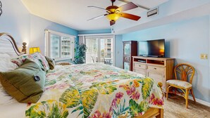 Une chambre à coucher avec un lit, un ventilateur de plafond, une télévision et une fenêtre.