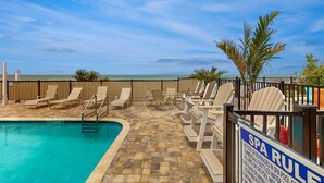 A pool area with lounge chairs and a spa rule sign.