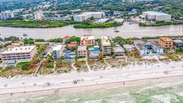 An aerial view of a coastal area with buildings, a beach, and a river.