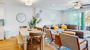 Ein modernes Wohnzimmer mit einem Holzesstisch, einer Couch und einem Deckenventilator.