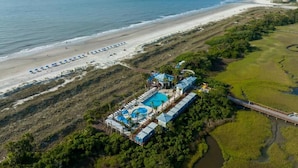 An aerial view of a resort with a beach, a swimming pool, and a bridge connecting to the mainland. - Marriott's SurfWatch Resort (Hilton Head Island)