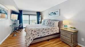 Une chambre à coucher comprenant un lit, une table de chevet, une lampe et un bureau avec une chaise.