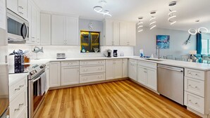 Une cuisine moderne avec des meubles blancs, un plancher en bois et un lave-vaisselle en acier inoxydable.