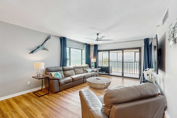 A modern living room with a leather sofa, a round coffee table, and a ceiling fan.