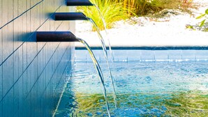 Piscina com água cristalina e parede com torneira.