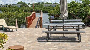 Eine Uferterrasse mit Picknicktischen, einer Liege und einem Verbotsschild für Schwimmen.