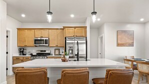 Una cocina moderna con armarios de madera, electrodomésticos de acero inoxidable y una isla grande con taburetes de bar.