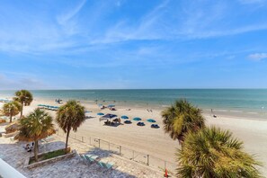 A beach with umbrellas and palm trees.