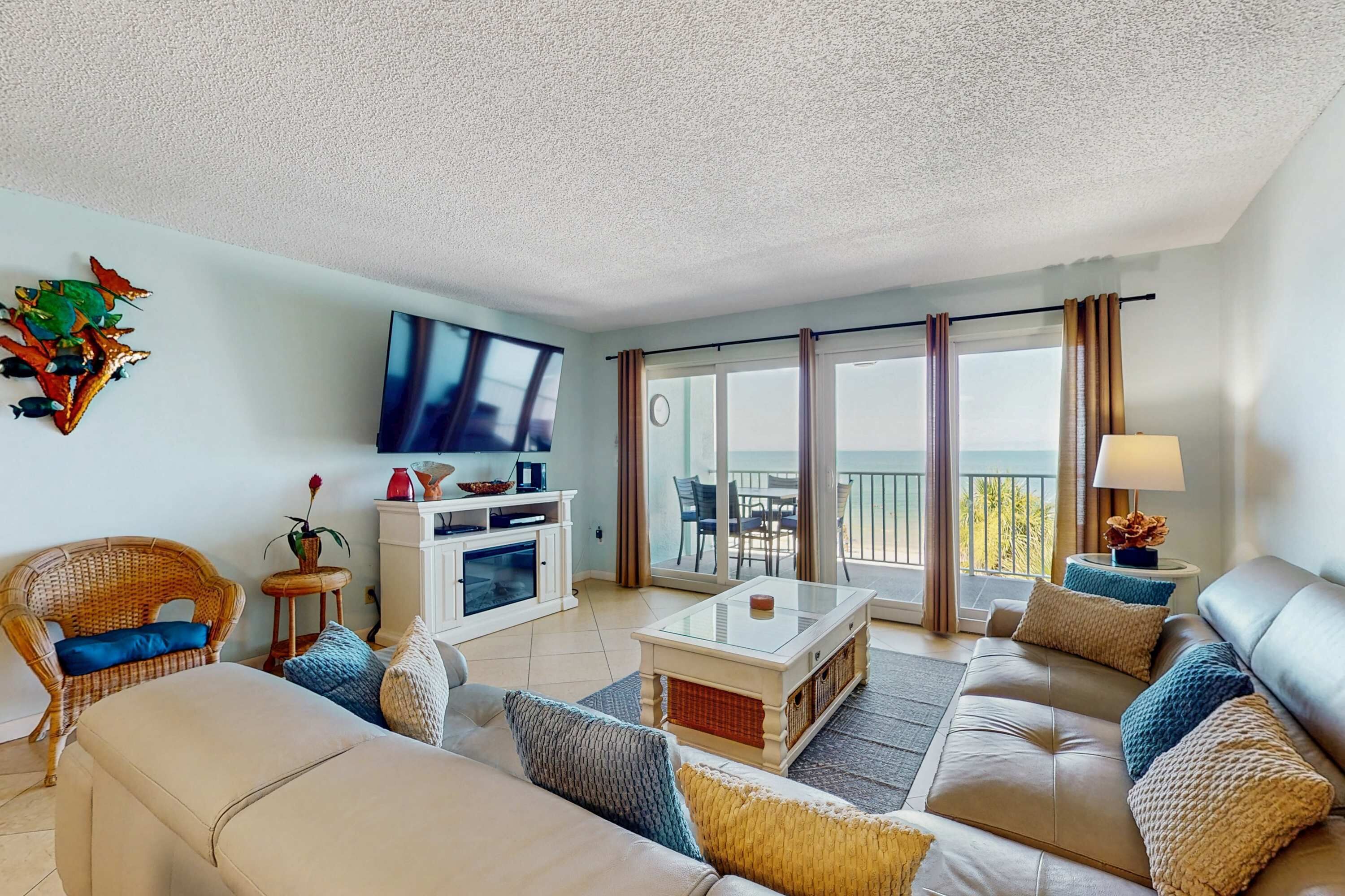 A living room with a sofa, coffee table, TV, and a balcony with a view.