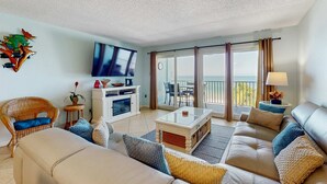 Een woonkamer met een bank, salontafel, televisie en een balkon met uitzicht.
