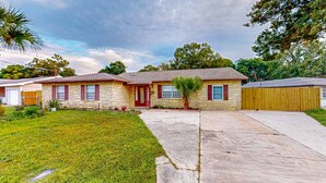 A two-story house with a front yard, a driveway, and a wooden fence.