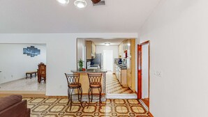 A modern kitchen with a central island, wooden cabinets, and a tiled floor.