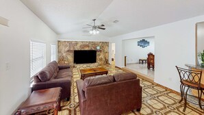 A spacious living room with a brown leather sofa, a wooden coffee table, and a stone accent wall.