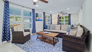 A living room with a sofa, two armchairs, a coffee table, and a ceiling fan.