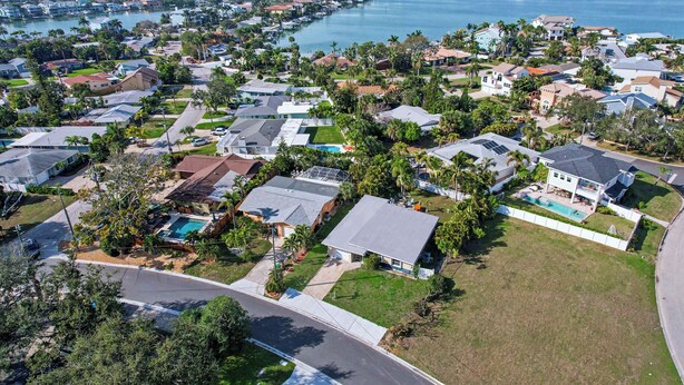 An aerial view of a residential area with houses, a swimming pool, and a marina.