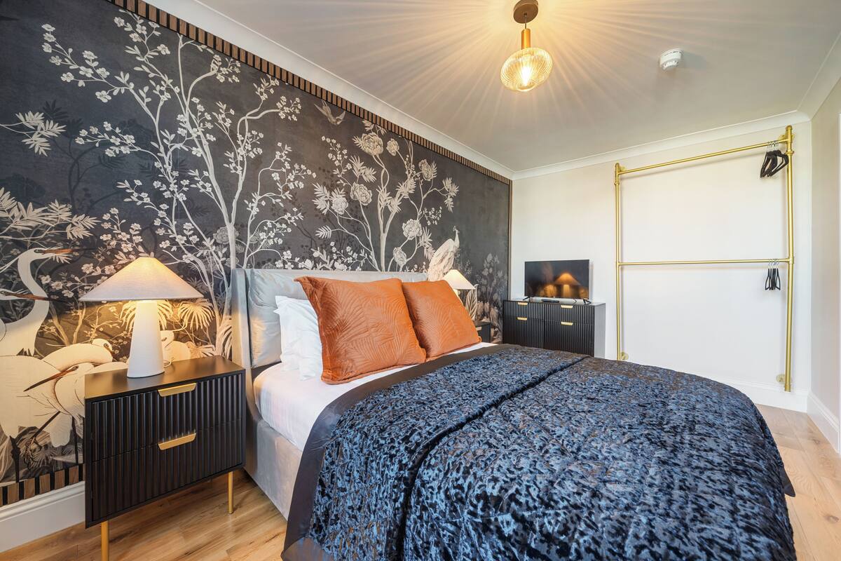 Una camera da letto con un letto, un comodino, una lampada e un affresco sulla parete.