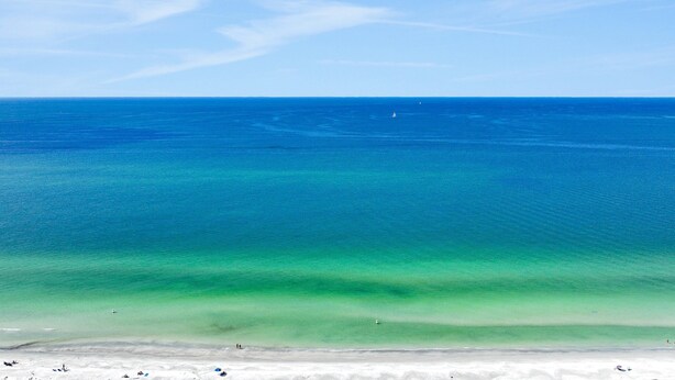 A beach with clear blue water and a sandy shore. - Beachfront condo with multiple balconies heated pool gym hot tub and AC (Clearwater Beach)