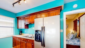 A kitchen with wooden cabinets, a white refrigerator, a coffee maker, and a water dispenser.
