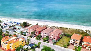 A coastal residential area with beachfront properties, a main road, and parked vehicles.