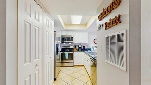 A kitchen with white cabinets, a microwave, an oven, and a sink.