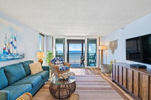 A living room with a sofa, armchair, coffee table, and TV stand. - Gorgeous updated and spacious condo with stunning beachfront view pool WD and AC (Indian Rocks Beach)