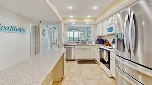 A modern kitchen with stainless steel appliances, white cabinetry, and a granite countertop.