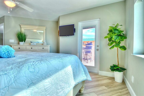 Un dormitorio con cama, cómoda, espejo, televisor y planta en maceta.