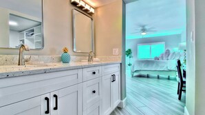 A modern bathroom with a large mirror, dual sinks, and a vanity with drawers. - 4th floor beachfront condo with private balcony views pool BBQ and AC (Indian Shores)