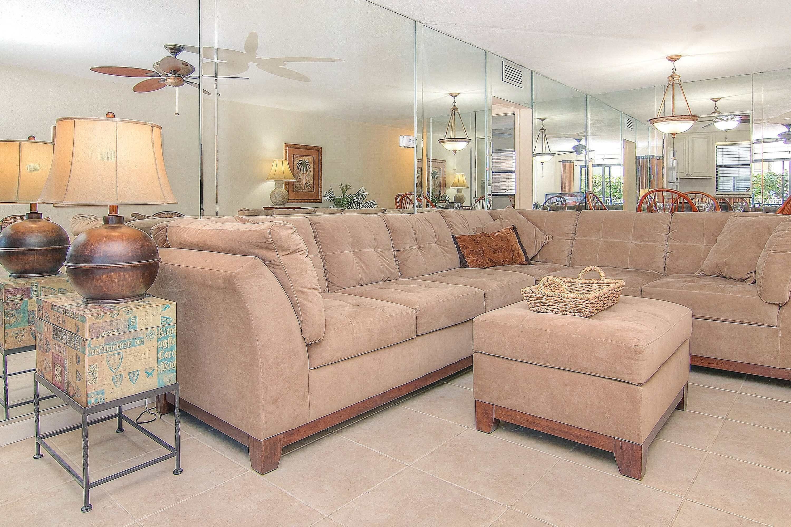 A living room with a sectional sofa, a small ottoman, and a side table with lamps.