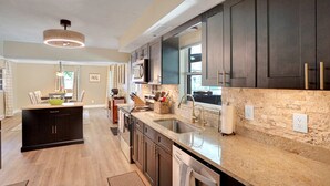 A modern kitchen with dark cabinetry, a granite countertop, and a central island. - Riverfront retreat with pool spa outdoor kitchen firepit dock sauna and games (Tampa)
